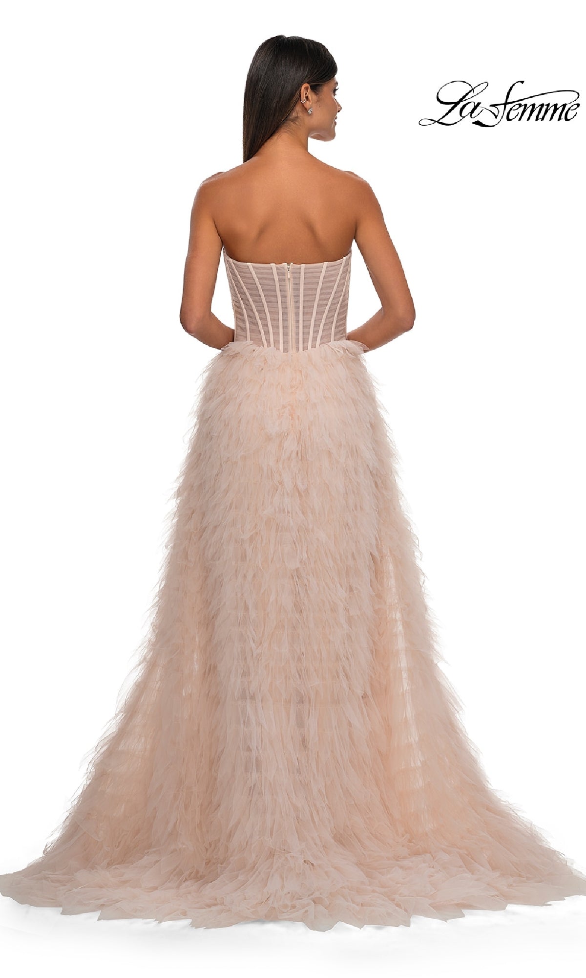 Woman in the Strapless Ruffled Prom Ball Gown: La Femme 32528, featuring a corset-style bodice and feathered, flowing skirt, shown from the back against a white background.